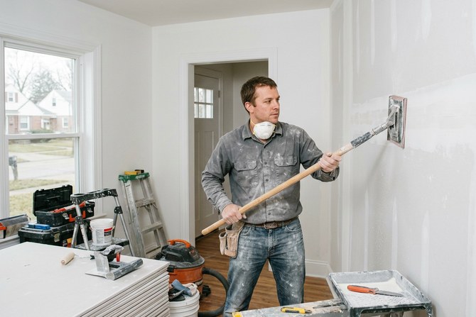 Technician sanding a wide freshly taped drywall joint with a pole sander